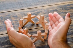 business-success-concept-wooden-table-top-view-hands-protecting-wooden-figures-people